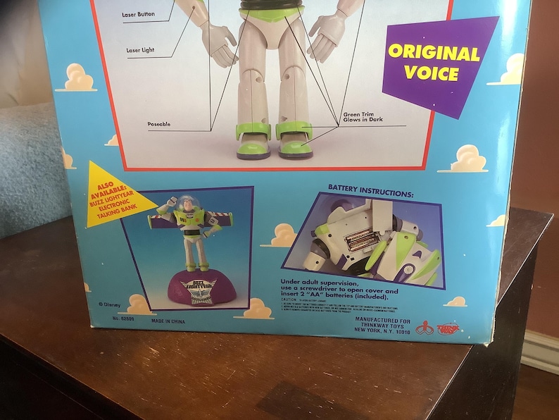Op de afbeelding: Een speelgoeddoos met Buzz Lightyear uit Toy Story. De doos is lichtblauw met afbeeldingen van het personage en de tekst "Original Voice". Het bevat een kleine afbeelding van het speelgoed en batterij-instructies.