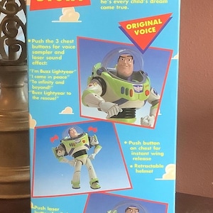Op de afbeelding: Blauwe doos voor de Buzz Lightyear Ultimate Talking Action Figure. De doos toont het Toy Story-logo en afbeeldingen van de Buzz Lightyear actiefiguur. Kenmerken zijn een stem sampler, laserstraal, uitklapbare vleugels en een intrekbare helm.