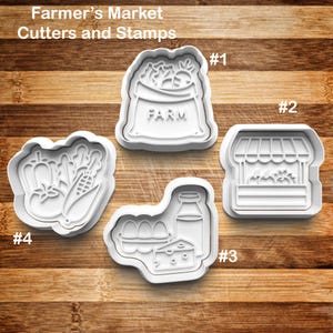 May include: White plastic cookie cutters and stamps with a farmer's market theme. The set includes shapes of a bag of produce with the word "FARM", a market stall, a collection of eggs, milk, and cheese, and vegetables.