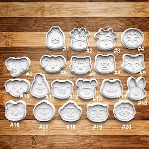 May include: Twenty white plastic cookie cutters shaped like various animals, including a giraffe, a sloth, a cat, a frog, a pig, a penguin, and an owl. Each cutter is numbered from 1 to 20.