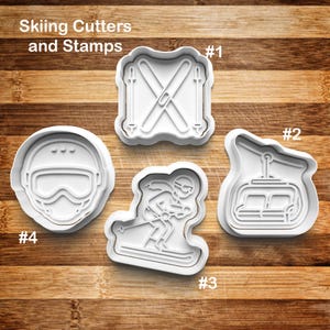 May include: White plastic cookie cutters and stamps with a skiing theme. The set includes shapes of skis, a ski lift, a skier, and a ski helmet. The text "Skiing Cutters and Stamps" is at the top of the image.