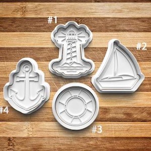 May include: Four white plastic cookie cutters shaped like a lighthouse, sailboat, anchor, and life preserver. The cutters are numbered 1 through 4.
