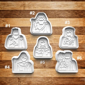 May include: Six white plastic cookie cutters shaped like different figures. The cutters are numbered 1 through 6. The figures are of people with different hairstyles and clothing.