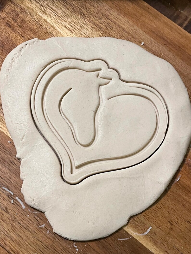 May include: A heart-shaped cookie cutter with a horse silhouette inside. The cutter is made of metal and is ready to be used to cut out cookies.