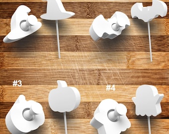 May include: Set of ten white Halloween themed push pins. The pins are shaped like a witch's hat, a bat, a pumpkin, and a ghost. Each pin has a number from 1 to 10.