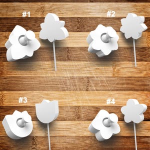 May include: Four white plastic push pins with different flower shapes. The push pins are numbered 1 through 4. The push pins are on a wooden surface.