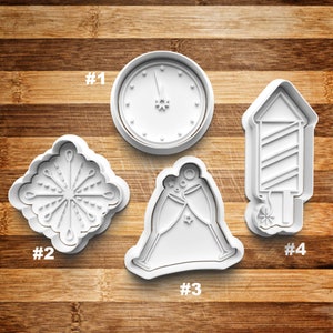 May include: Four white plastic cookie cutters shaped like a clock, a snowflake, a champagne toast, and a firecracker. The cutters are numbered 1 through 4.