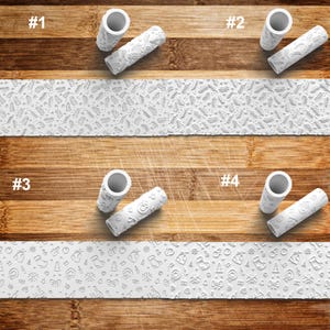 May include: Four white rolling pins with different embossed designs. The designs include a repeating pattern of leaves, a repeating pattern of snowflakes, a repeating pattern of Christmas trees, and a repeating pattern of Christmas ornaments. The rolling pins are on a wooden surface.