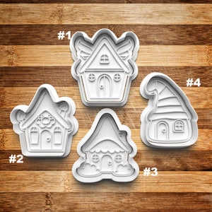May include: Four white plastic cookie cutters shaped like houses. The cutters are numbered 1 through 4. The houses have different styles, including a house with wings, a house with a mushroom roof, a house with a cloud base, and a house with a pointed roof.