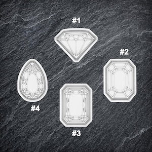 May include: Four different cookie cutters shaped like diamonds. The cutters are numbered 1 through 4. The cutters are white and made of plastic.