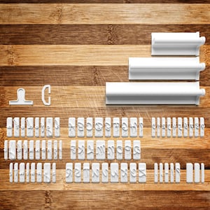 May include: White plastic alphabet and number cookie cutters and tools. The set includes individual letter and number stamps, plus several larger tools for shaping dough. The cutters are arranged on a wooden surface.