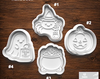 May include: Four white plastic cookie cutters featuring Halloween designs: a witch with a lollipop and cauldron, a jack-o'-lantern pumpkin, a bubbling cauldron, and a ghost holding a bag labeled Trick or Treat. Each cutter is numbered one through four.