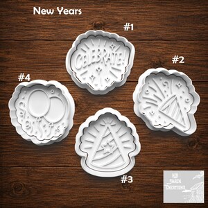 May include: Four white plastic cookie cutters with New Year's themes. Cutter #1 features the text CELEBRATE! with star accents. Cutter #2 shows a party popper. Cutter #3 depicts a party hat with a star. Cutter #4 displays two balloons with ribbons.