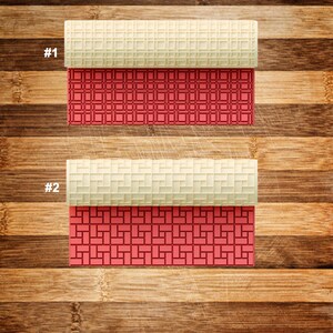 May include: Two textured rolling pins with geometric patterns. The top portion of each pin is a light beige color, while the bottom section features a red geometric design. The background is a wooden surface.