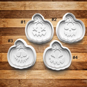 May include: Four white plastic pumpkin cookie cutters with different facial expressions. The cutters are numbered 1 through 4.