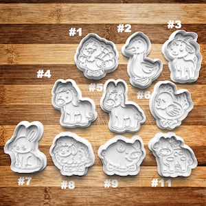 May include: Set of 11 white plastic cookie cutters shaped like farm animals, including a turkey, duck, goat, horse, donkey, chicken, rabbit, sheep, pig, and cow. The cutters are numbered 1 through 11.