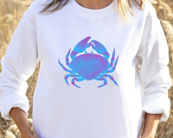 May include: White sweatshirt featuring a large, stylized crab graphic. The crab design is a gradient of blue and pink hues. The sweatshirt has long sleeves and a crew neck, suitable for casual wear.