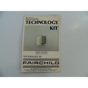 Pode incluir: Um cartão branco com o texto "TECHNOLOGY KIT" em letras pretas. O cartão também apresenta uma pequena imagem de um chip de circuito integrado prateado. O texto "BINARY COUNTER (SIMILAR TO THE 74177)" está impresso abaixo da imagem. O texto "TECHNOLOGY BY FAIRCHILD" está impresso abaixo da descrição do contador. O cartão também inclui o endereço da empresa e uma declaração sobre onde o produto é fabricado.
