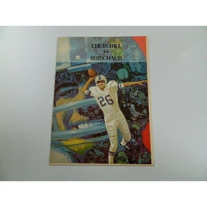 May include: A vintage program for a football game between Churchill and Robichaud. The cover features a colorful illustration of a football player in action, wearing a blue jersey with the number 26.