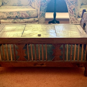 May include: A wooden storage bench with a slatted front and a hinged top. The bench has a decorative carved design on the front and sides. The bench is brown and has a distressed finish.