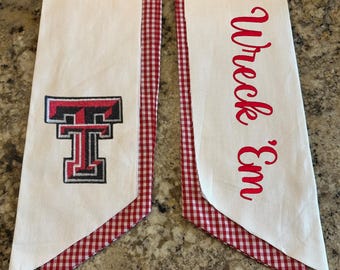 May include: Two white fabric banners with red and black accents. One banner features the Texas Tech logo, the other reads "Wreck 'Em" in red script. The edges are trimmed with red and white gingham.