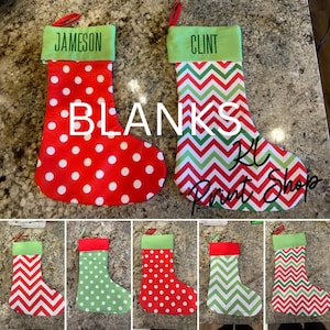 May include: Christmas stockings with green tops and red hanging loops. One stocking has white polka dots on a red background, the other has a red, green, and white chevron pattern. The word "BLANKS" is printed on the stockings.