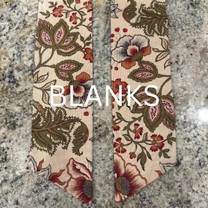 May include: Two beige fabric strips with a floral pattern in red, brown, and blue. The word "BLANKS" is printed in white across the center of the image. The floral design includes large stylized flowers and leaves.