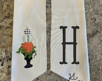 May include: Two off-white fabric banners. One banner features an embroidered arrangement of pumpkins in a black urn. The other banner displays a large black letter "H". The text "KL Print Shop" is at the bottom.