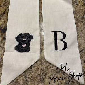 May include: White graduation sash with black embroidery of a Labrador Retriever and the letter "B".