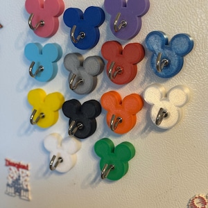 Könnte beinhalten: Ein Set mit 12 bunten Mickey-Maus-Kopf-Haken mit silbernen Haken. Die Haken sind aus Kunststoff und eignen sich perfekt zum Aufhängen von Schlüsseln, Schmuck oder anderen kleinen Gegenständen.