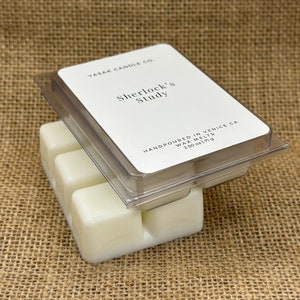May include: A clear plastic container of wax melts with four individual cubes. The label reads "YASAK CANDLE CO. Sherlock's Study HANDPOURED IN VENICE CA WAX MELTS 2.50 oz 171g"