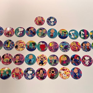Könnte beinhalten: Eine Sammlung von 30 runden, bunten Plastik-Spielmarken mit verschiedenen Peanuts-Charakteren. Die Spielmarken haben ein psychedelisches, Batik-Design mit Bildern von Snoopy, Charlie Brown, Lucy, Linus und anderen Peanuts-Charakteren.