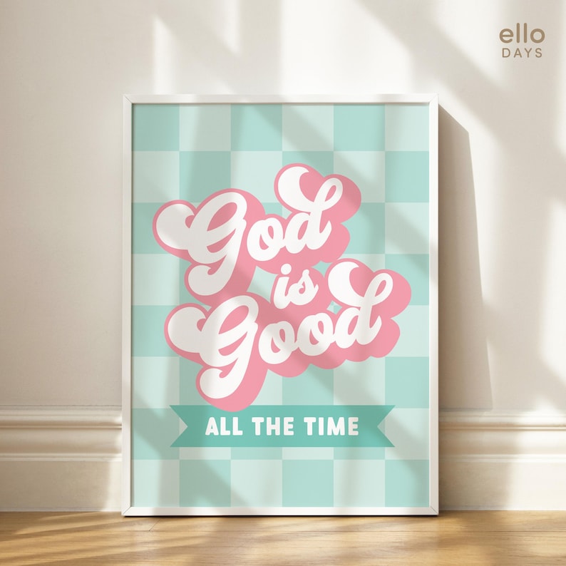 May include: A white framed print with a light blue and white checkered background. The text "God is Good" is in pink with a white outline and a banner below that reads "All the Time".