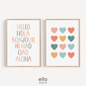 May include: Two framed prints with a white background. The print on the left has the words "HELLO", "HOLA", "BONJOUR", "NI HAO", "CIAO", and "ALOHA" written in colorful letters. The print on the right has a pattern of 12 colorful hearts.