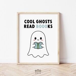May include: A white framed print with a black and white illustration of a ghost reading a book. The text on the print reads "Cool Ghosts Read Boooks".