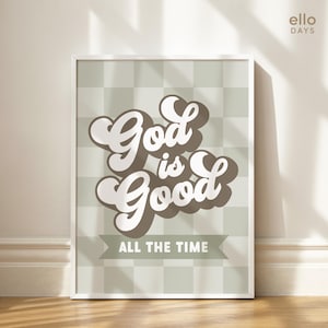 May include: A framed print with a green and white checkered background. The text "God is Good" is written in a brown and white retro font. The text "All the Time" is written in a smaller font below the main text.