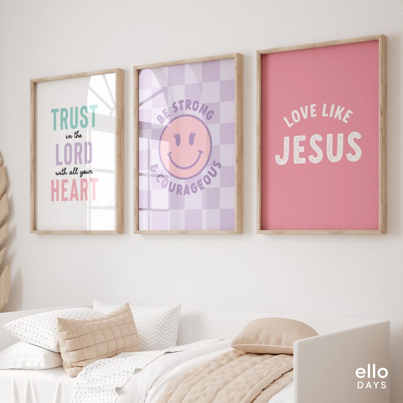 May include: Three framed prints with inspirational quotes. The first print has a light pink background with the text "TRUST in the LORD with all your HEART". The second print has a purple and white checkered background with a pink smiley face and the text "BE STRONG & COURAGEOUS". The third print has a pink background with the text "LOVE LIKE JESUS".