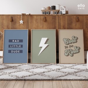 May include: Three framed prints with motivational messages. The first print is blue with the text "RAD LITTLE DUDE". The second print is green with a white lightning bolt. The third print is beige with the text "Cool to be Kind" in a retro font.