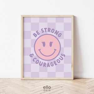 May include: Purple and pink motivational print with a smiling face and the text "Be Strong & Courageous" on a checkered background.