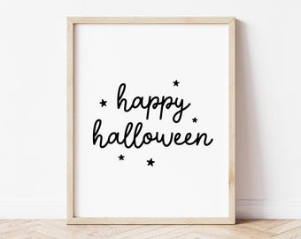 May include: A framed print with the words "happy halloween" in black script, accented by small black stars. The print has a white background and a light wood frame, perfect for Halloween decor.