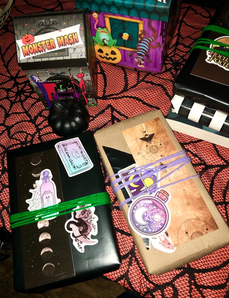 May include: Halloween-themed gift boxes and wrapped packages with stickers and twine. The boxes feature spooky illustrations and the text "Monster Mash." The wrapped gifts are adorned with stickers of moons, potions, and celestial designs.