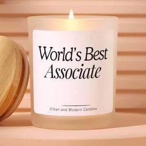May include: A frosted glass candle with a wooden lid, featuring a white label that reads World's Best Associate and Urban and Modern Candles. The text No harmful chemicals like phthalates, parabens, or sulfates is visible in the upper right corner.