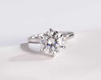 May include: A silver ring with a large, round, clear diamond.