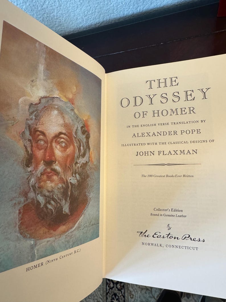 Może przedstawiać: Otwarta książka zatytułowana "The Odyssey of Homer" autorstwa Alexandra Pope'a, z ilustracjami klasycznych wzor&oacute;w. Książka zawiera ilustrację Homera i tekst z "The Easton Press, Norwalk, Connecticut". Jest to wydanie kolekcjonerskie oprawione w prawdziwą sk&oacute;rę.