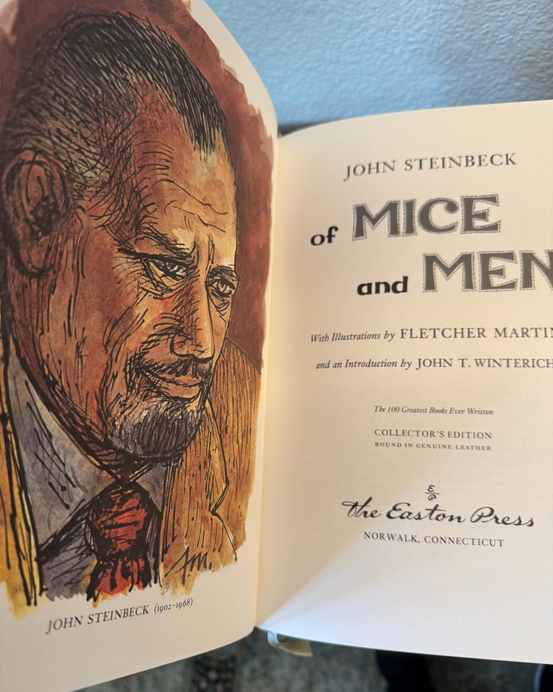 Może przedstawiać: Otwarta książka z tytułem "Of Mice and Men" i portretem Johna Steinbecka. Książka jest wydaniem kolekcjonerskim, oprawionym w prawdziwą sk&oacute;rę, wydanym przez The Easton Press.