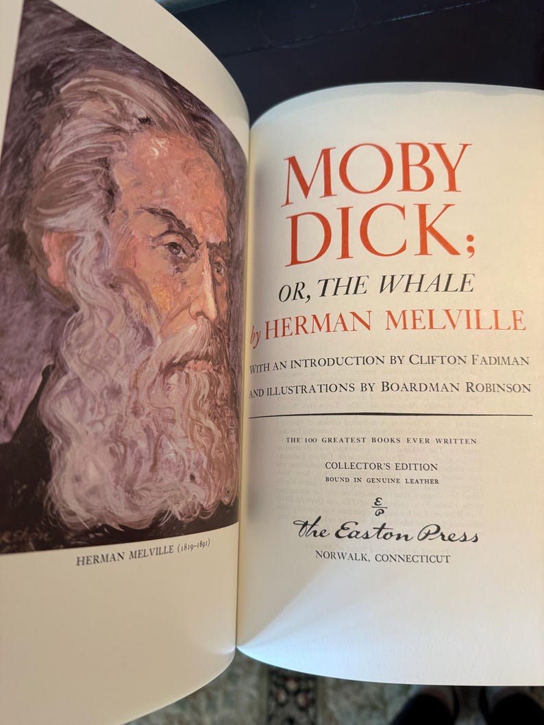 Może przedstawiać: Otwarta książka z tytułem "MOBY DICK" w czerwonych literach. Imię i nazwisko autora, Herman Melville, r&oacute;wnież w kolorze czerwonym. Portret Hermana Melville'a znajduje się na lewej stronie. Książka jest wydaniem kolekcjonerskim The Easton Press.