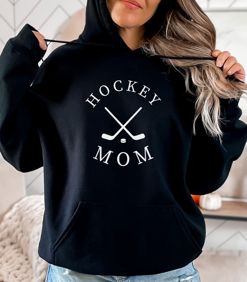 May include: Black hoodie with a white graphic that says "Hockey Mom" with crossed hockey sticks and a puck.