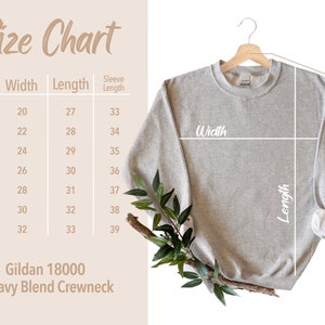 May include: A light gray Gildan 18000 Heavy Blend Crewneck sweatshirt hangs on a wooden hanger. A size chart shows measurements in inches for width, length, and sleeve length, ranging from size S to 4XL.