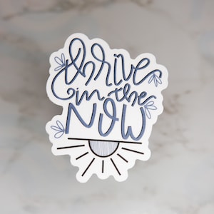 May include: White sticker with blue lettering that reads "Thrive in the NOW" with a stylized sun graphic below.