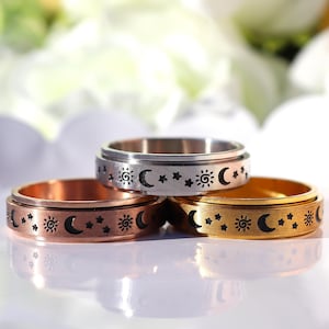 May include: Three spinning rings with a sun, moon, and stars design. The rings are made of silver, gold, and copper.